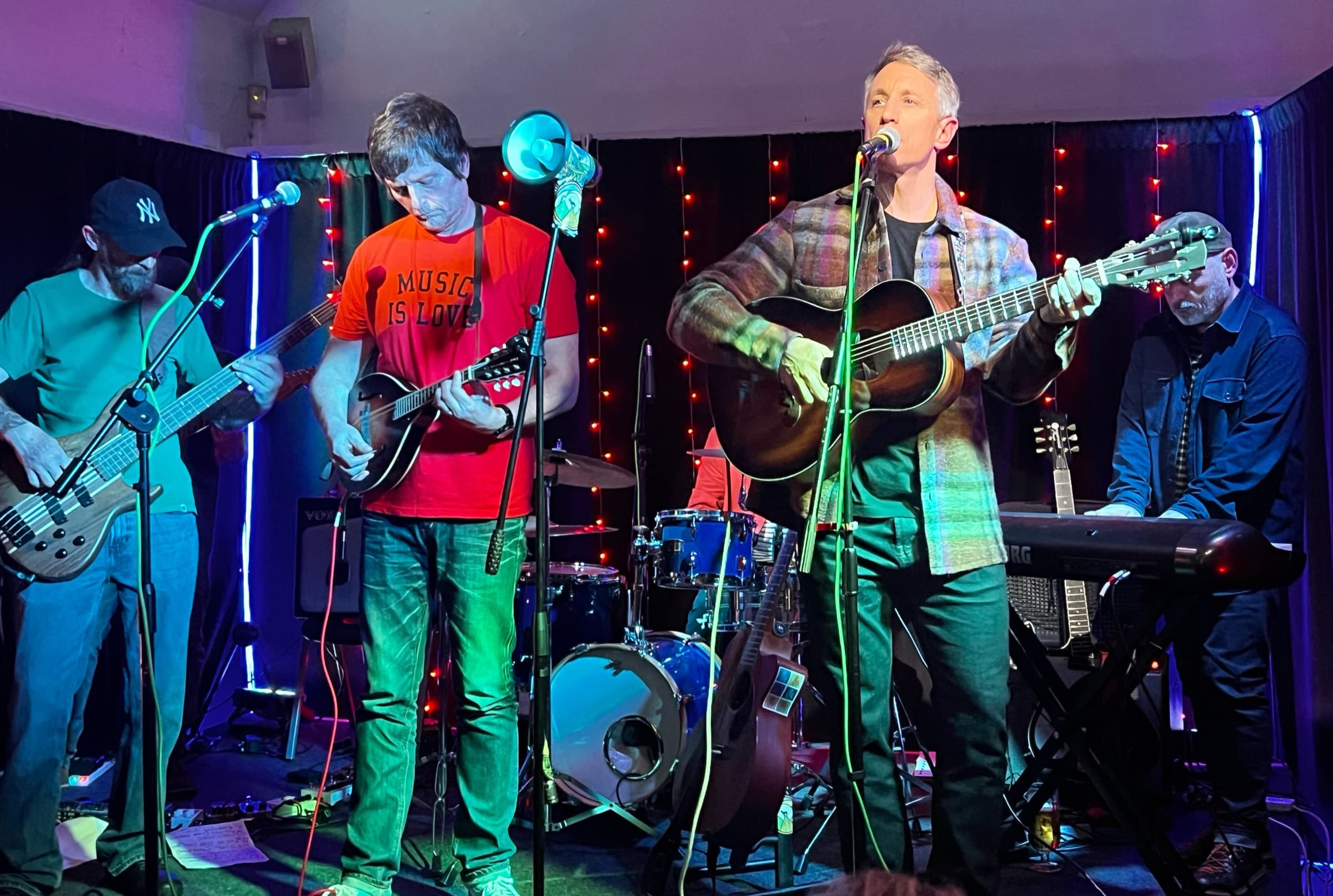 Professor Yaffle: a five-piece band on the stage under strings of red lights: bass, two guitars and keys